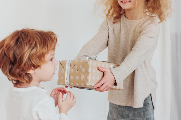 Foto ragazza che dà una scatola regalo al fratello a casa