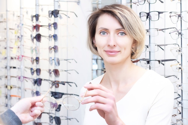 Ragazza con gli occhiali per la vista. provare gli occhiali in un negozio di ottica.