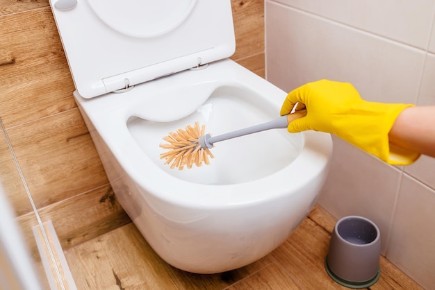 A girl in gloves cleans the toilet bowl with a brush with a special disinfectant