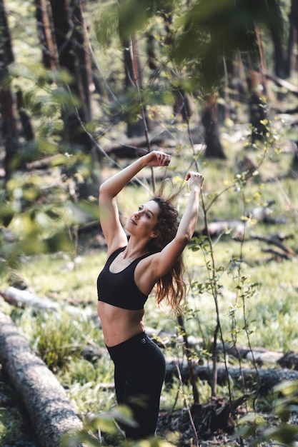 Foto la ragazza fa sport nella foresta. nella posizione del loto. esercizi, ginnastica, rilassamento. uno stile di vita sano.