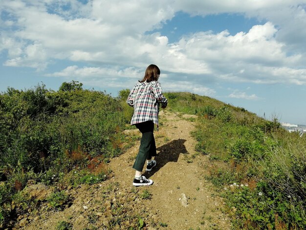 Photo girl going forward on the mountain path during summer day