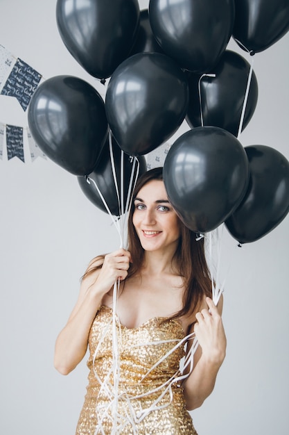 Girl in a gold dress with black balloons