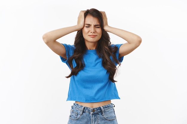 Girl got things messed up dont know how solve problem she made Troubled and frustrated concerned young female brunette in blue tshirt holding head and frowning calm down during panic