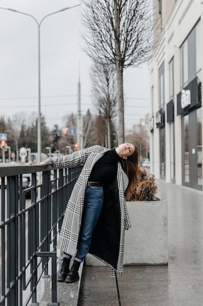 a girl in a gray coat and jeans holds on to the handrail