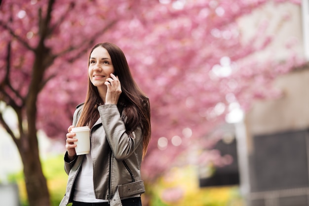 Girl in a great mood posing for a cup of coffee on Sakura