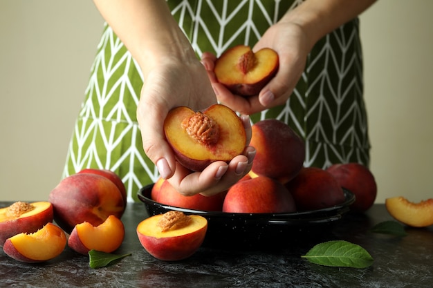 Photo girl in green apron holds ripe peach fruits