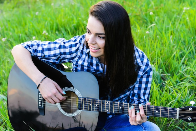 ギターを弾く緑の牧草地の女の子