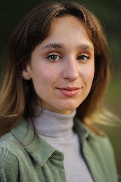 girl in a green shirt and blue jeans in the autumn forest girl holding a maple leaf in her hands