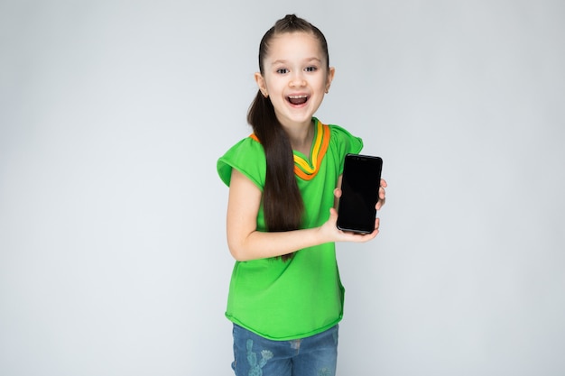 Girl in green t-shirt and blue jeans with smartphone