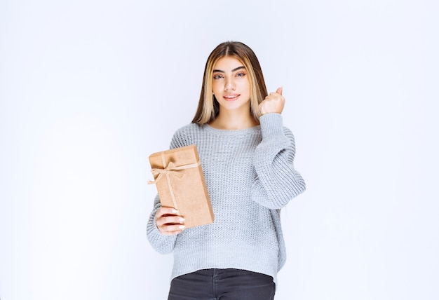 Photo girl in grey sweater holding a cardboard gift box.