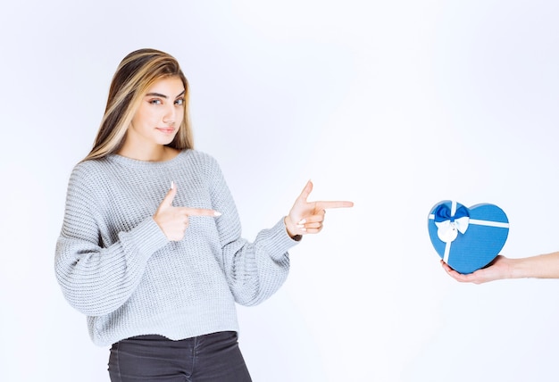 Girl in grey sweatshirt showing the blue heart shape gift box that is being offered to her.