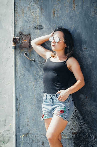 Photo girl grunge glasses is near a grey door and wall