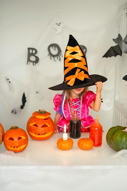 Girl in guise of witch hides face behind huge hat on Halloween