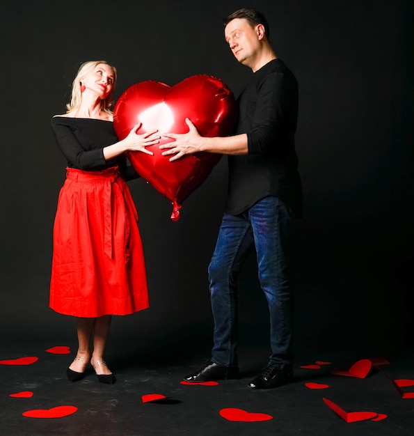 A girl and a guy hold a heart balloon inflatable valentine happiness flirt on the floor hearts are