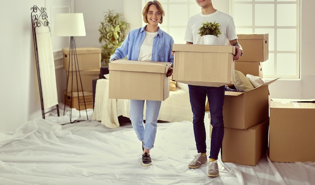 A girl and a guy holding boxes for moving the hands and looking inside box