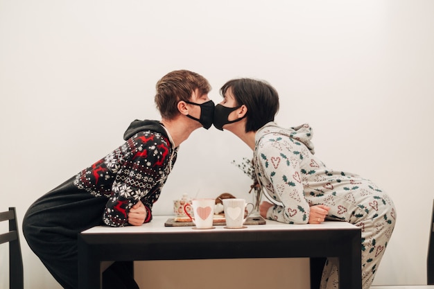 Девушка и парень целуются в масках на карантине COVID-19.