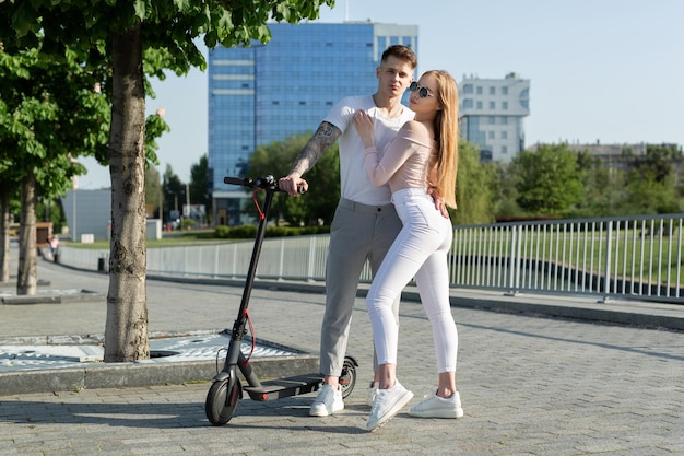 Ragazza e ragazzo camminano su scooter elettrici per la città una coppia innamorata su scooter