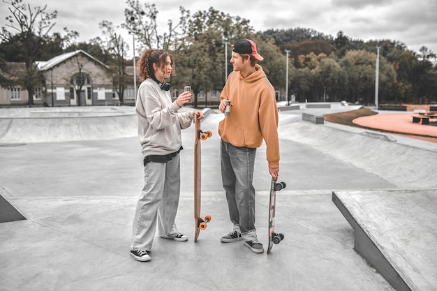 Girl and guy with skateboards talking in park