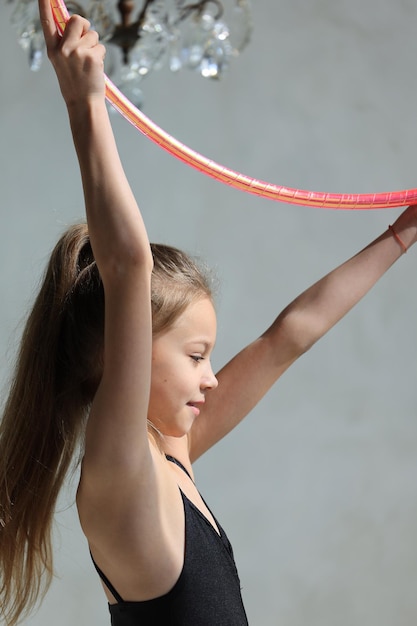 Girl gymnast in a black leotard with a with hoop on a grey background rhythmic gymnastics concept hi