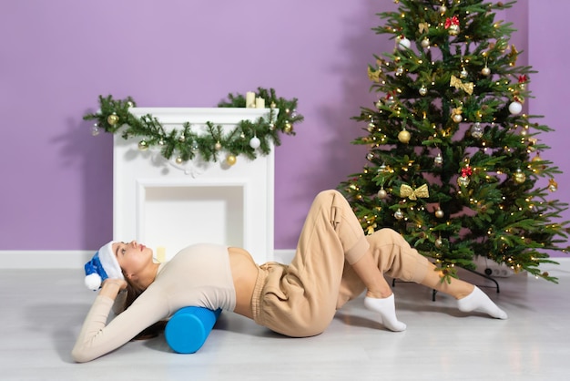 A girl, a gymnast, is doing stretching near the new year tree