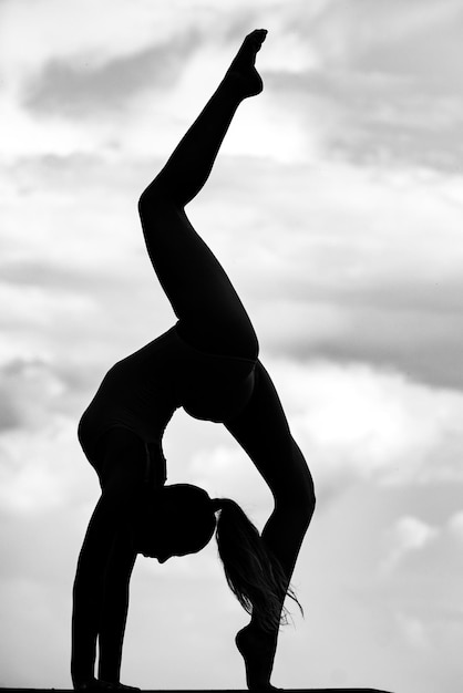 Girl gymnastic silhouette on sky young slender girl doing acrobatic stunt gymnast in backlight