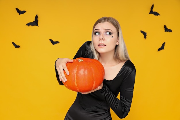 A girl in a halloween costume with a pumpkin in her hands