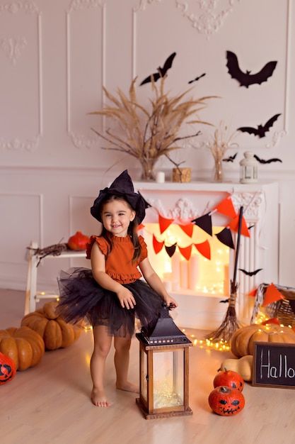 girl in halloween witch costume with pumpkins