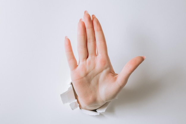 Girl hand breaks white paper and shows a gesture.