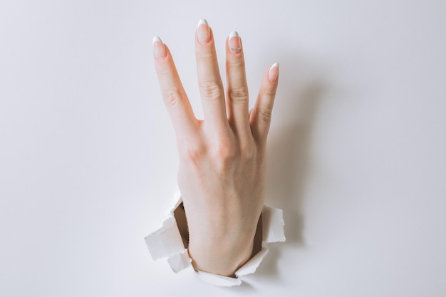 Girl hand breaks white paper and shows a gesture