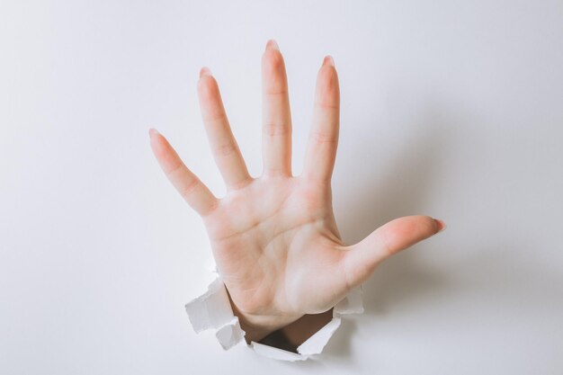 Girl hand breaks white paper and shows a gesture