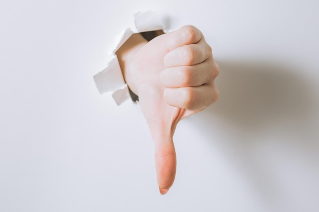 Girl hand breaks white paper and shows a gesture