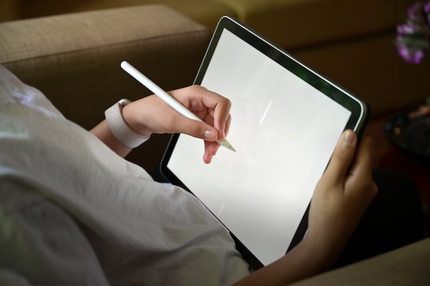 girl hand drawing sketches with touchscreen surface modern tablet while sitting sofa. 