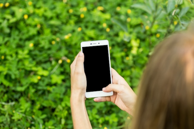 Mano della ragazza che tiene lo schermo bianco dello smartphone. concetto di business