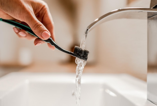 Girl hand holding tooth brush under running water