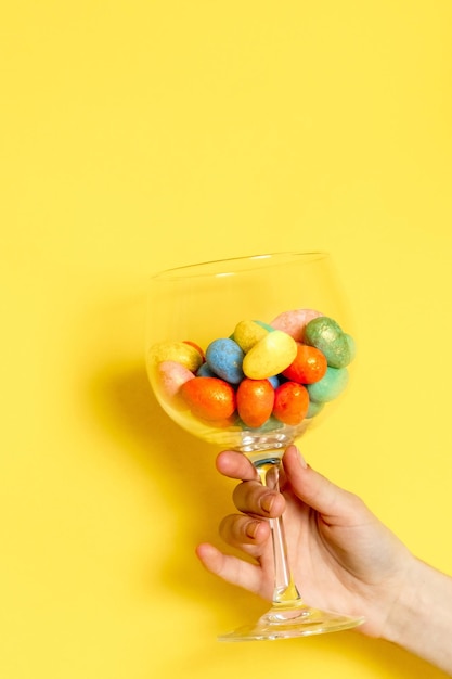 The girl hand holds a glass with easter eggs