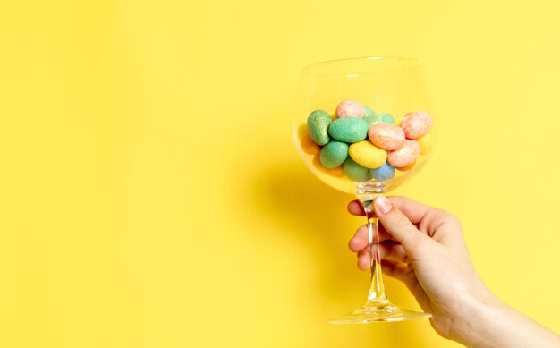 The girl hand holds a glass with easter eggs