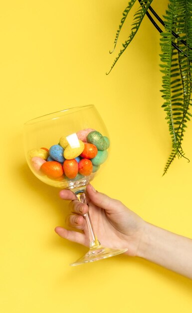 The girl hand holds a glass with easter eggs