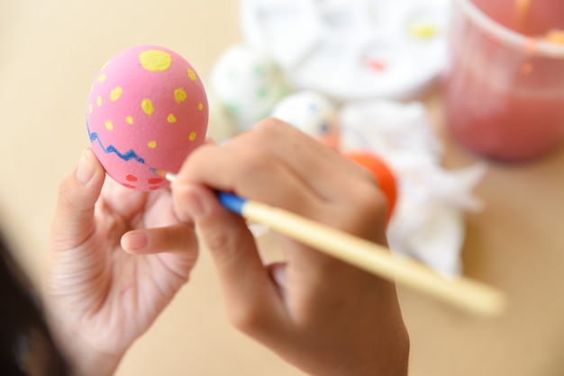 A girl hand painting Easter eggs. Happy family preparing for Easter.