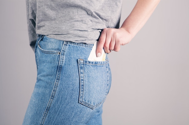 Girl hand putting money in jeans pocket