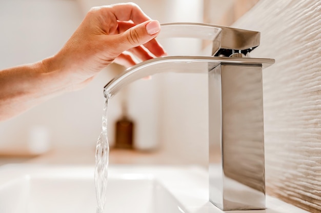 Girl hand and water faucet in bathroom