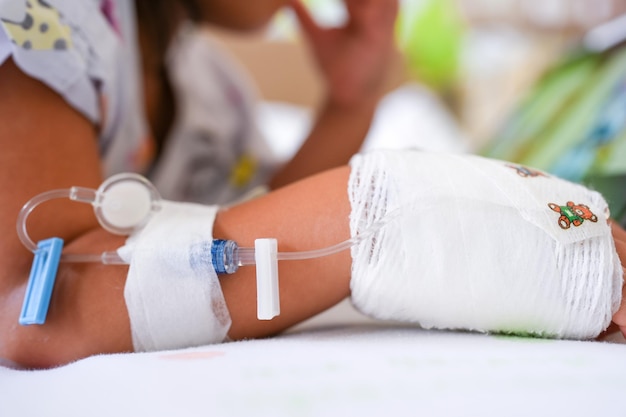 Girl hand with drip infusion on bed