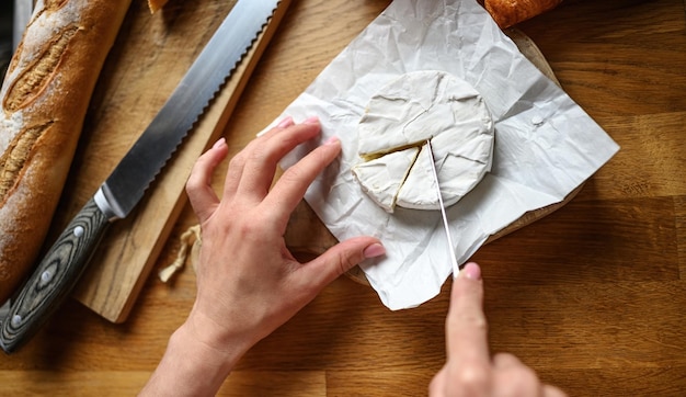 Girl hands cut brie at kitchen delicious bakery pastry and camembert for healthy morning meal