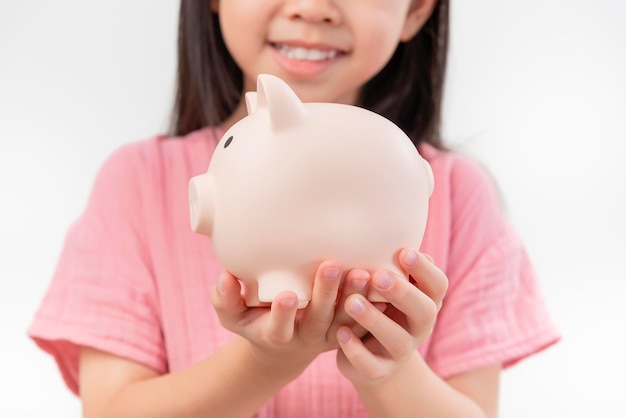 소녀의 손에는 분홍색 돼지 저금통이 있습니다. 돈을 절약하거나 투자를 절약하는 개념