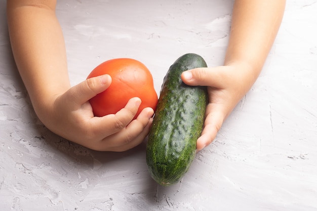 Girl hands holding fresh seasonal vegetable. Cucumber, tomatoe. Flat lay