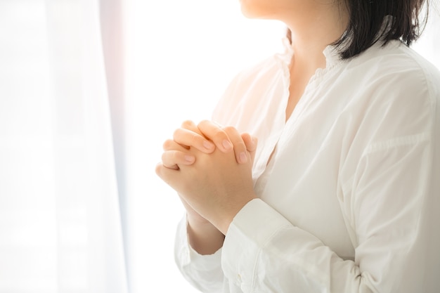 Руки девушки молятся богу. Молодая женщина молится о Божьем благословении желающим лучшей жизни. Просите прощения и верьте в добро. Христианская жизненная кризисная молитва богу