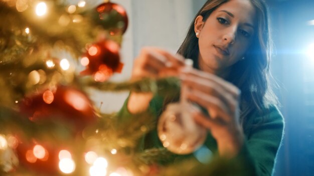 写真 女の子がクリスマスツリーにボールを吊るす