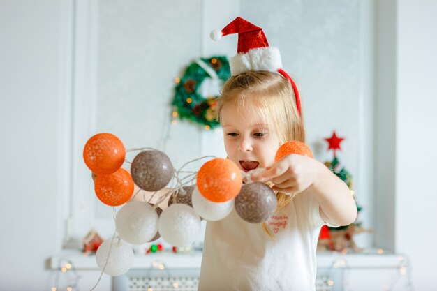 女の子がクリスマスに花輪を掛けます。