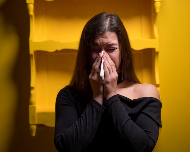 Girl has a cough. Female on yellow wall