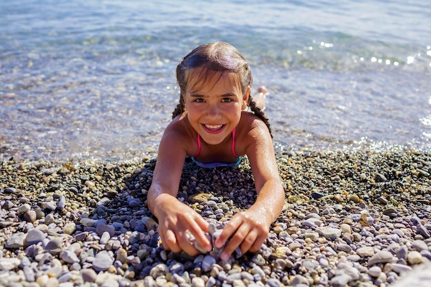 女の子はジュネーブ湖の小石のビーチで楽しい夏休みと旅行を楽しんでいます