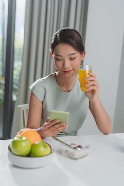 The girl has a healthy breakfast at the morning while checking her email on mobile